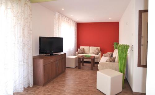 a living room with a tv on a wooden dresser at Bodensee Hotel Storchen in Uhldingen-Mühlhofen