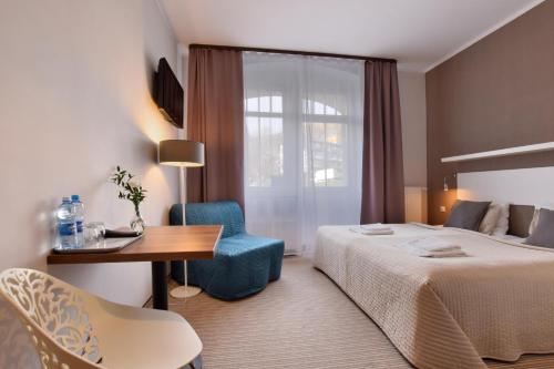 une chambre d'hôtel avec un lit, une table et une chaise dans l'établissement Willa Na Cichej, à Szklarska Poręba