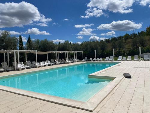 una grande piscina con sedie e cielo azzurro di Agriturismo La Masseria - La casa tra gli alberi a Cugnoli
