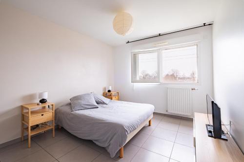 Habitación blanca con cama y TV en Appartement T2 neuf - Grande Terrasse de 25m2, en Saint-Priest