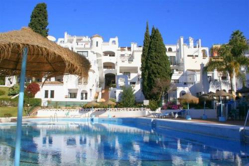 een groot zwembad voor een wit gebouw bij 2 bedroom apartment with pool and barbecue in Arroyo de la Miel