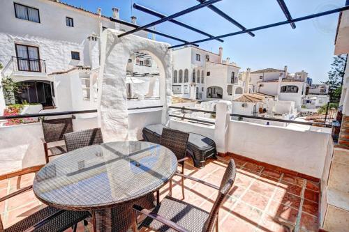 een terras met een tafel en stoelen op een balkon bij 2 bedroom apartment with pool and barbecue in Arroyo de la Miel