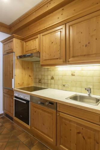 a kitchen with wooden cabinets and a sink at Alpasella Ferienwohnungen in Sankt Gallenkirch
