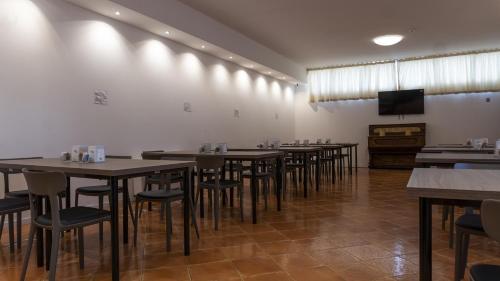 a dining room with tables and chairs and a flat screen tv at Hotel Rex Milano in Milan