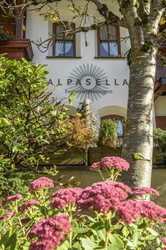 a tree and pink flowers in front of a building at Alpasella Ferienwohnungen in Sankt Gallenkirch