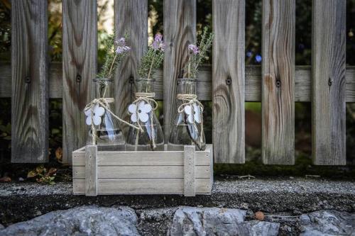 a wooden box with three glass jars filled with flowers at Alpasella Ferienwohnungen in Sankt Gallenkirch