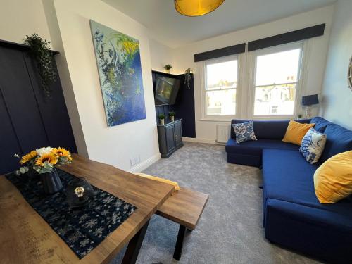 a living room with a blue couch and a table at Seaside Apartment close to beach, town, station in Broadstairs
