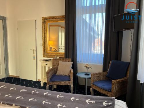 a hotel room with two chairs and a mirror at Pension Marie Luise 253 - Zimmer Meerschnecke in Juist