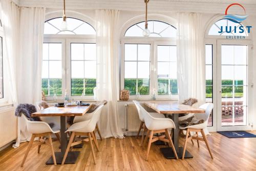 a dining room with two tables and chairs and windows at Pension Marie Luise 253 - Zimmer Meerschnecke in Juist