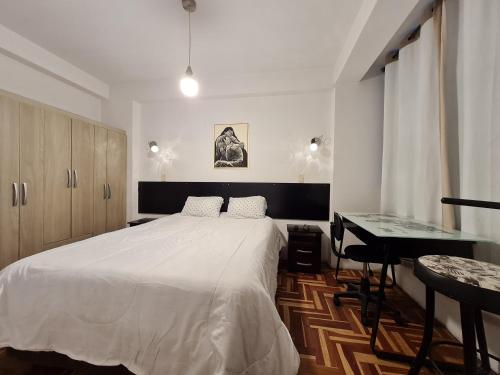 Schlafzimmer mit einem großen weißen Bett und einem Schreibtisch in der Unterkunft Apartment Centric Inti 2 in Cusco