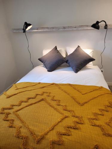 a bed with two pillows and a yellow blanket at Apartamento Estoril in Estoril