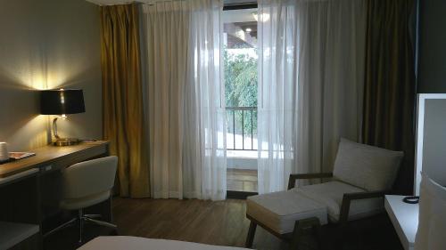 a hotel room with a desk and a chair and a window at Wyndham Garden Detroit Metro Airport in Romulus