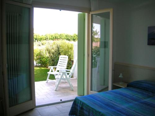 - une chambre dotée d'une porte s'ouvrant sur une terrasse avec une chaise dans l'établissement Residence Le Palme, à Lido di Jesolo