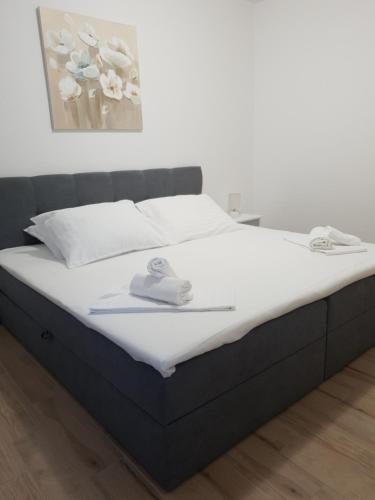 a bed with white sheets and shoes on it at Apartments Habek 2 in Vrboska