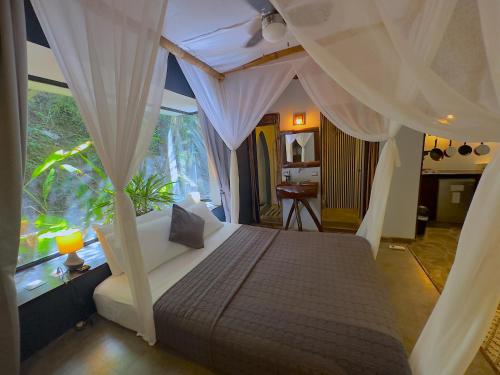 una camera con letto a baldacchino e finestra di Canaima Chill House a Santa Teresa Beach