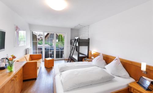 a bedroom with a bed and a couch and a desk at Bodensee Hotel Storchen in Uhldingen-Mühlhofen