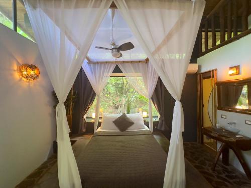 um quarto com uma cama de dossel e uma ventoinha de tecto em Canaima Chill House em Santa Teresa