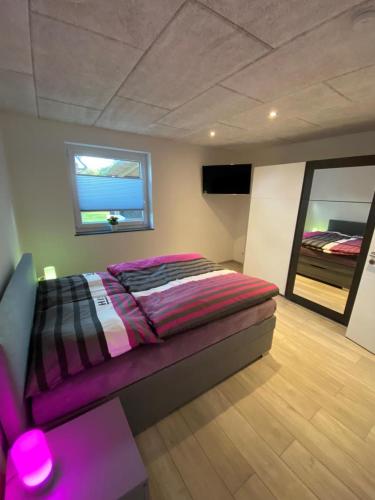 1 dormitorio con 1 cama con edredón morado y ventana en NEU! Modernes Ferienhaus Schwanbeck mit Whirlpool-Option, en Dassow