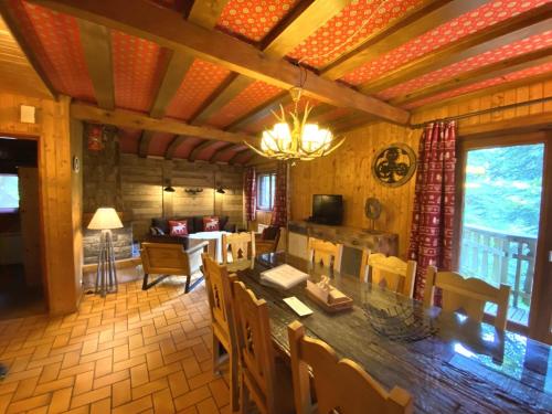 a dining room and living room with a table and chairs at LE TRAPPEUR Chalet en bois in La Bresse