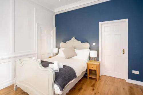 1 dormitorio con cama blanca y pared azul en Orchard Street: 1BR with Garden en Bath