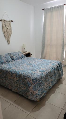 a bed with a blue comforter in a bedroom at "Valentino hostel" in Ezeiza