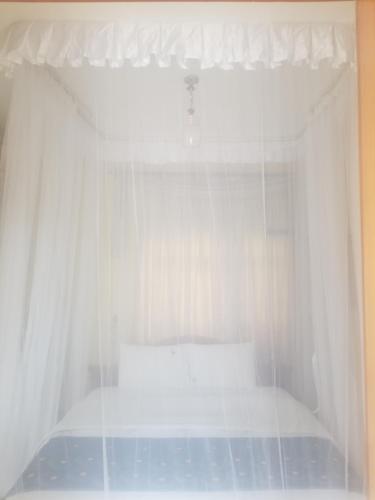 - une chambre avec un lit blanc et des rideaux blancs dans l'établissement Spannet Suites, à Mbarara