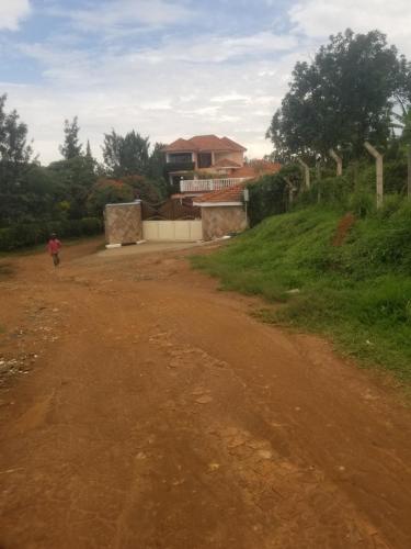 Una persona che cammina lungo una strada sterrata di fronte a una casa di Spannet Suites a Mbarara