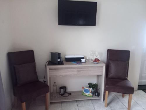 duas cadeiras sentadas ao lado de uma secretária com uma televisão na parede em JustB em Riemst