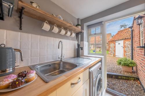 a kitchen with a sink and a window at Wishing Well Cottage in North Creake