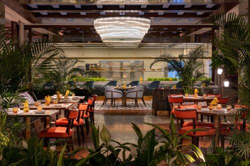 a restaurant with tables and chairs and plants at Waldorf Astoria Cairo Heliopolis in Cairo