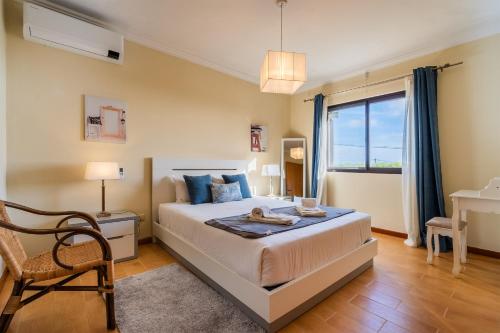 a bedroom with a bed and a desk and a window at Quinta D. Maria & Inês in Vila Franca do Campo