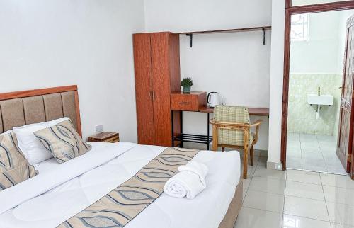 1 Schlafzimmer mit einem großen Bett und einem Badezimmer in der Unterkunft VIJIJI HOTEL & CONFERENCE in Eldoret