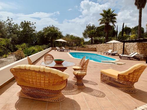 un patio con sillas, una mesa y una piscina en Villa Botanica, en Silves