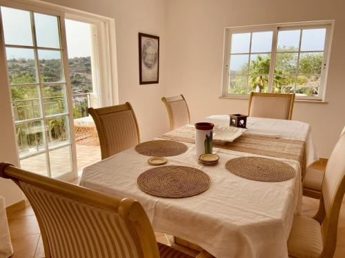 comedor con mesa, sillas y ventanas en Villa Botanica, en Silves