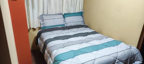 Cama con sábanas y almohadas azules y blancas en C&B APARTAMENTOS, en Jauja