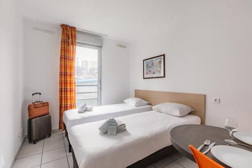 リヨンにあるAppart'City Classic Lyon Vaise St Cyrのベッドルーム1室(ベッド2台、テーブル、窓付)