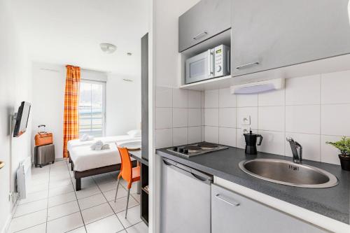 里昂的住宿－Appart'City Classic Lyon Vaise St Cyr，一个带水槽的厨房和一张位于客房内的床