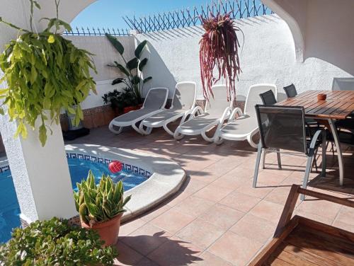 een patio met stoelen, een tafel en een zwembad bij Beautiful Holiday Villa with heated private pool, Los Cristianos in Los Cristianos