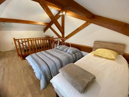 Cette chambre mansardée comprend 2 lits et des poutres apparentes. dans l'établissement LE LOFT AUX MIMOSAS - BORMES LES MIMOSAS - PISCINE, à Bormes-les-Mimosas