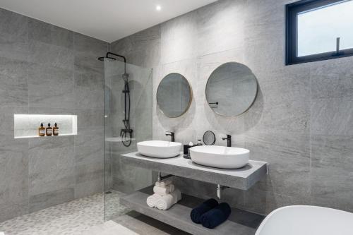 a bathroom with two sinks and two mirrors at Kove Samui - Absolute Beachfront Villas in Koh Samui 
