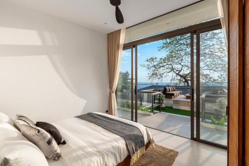 a bedroom with a bed and a large glass window at Kove Samui - Absolute Beachfront Villas in Koh Samui 