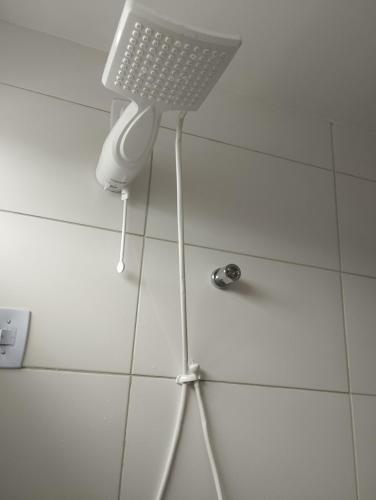 a shower head in a bathroom with white tiles at Residencial Ilha de Capri in Campina Grande