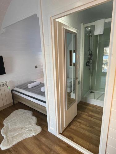 a bathroom with a bed and a shower and a mirror at Highland Stays - The Oaks Studio Pod in Fort William
