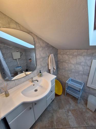 een badkamer met een wastafel en een spiegel bij Apartmani Vuković Punat in Punat
