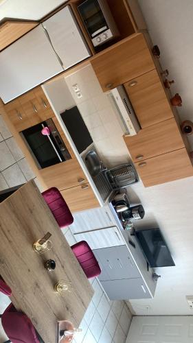 une vue aérienne d'une cuisine avec des armoires en bois et des chaises roses dans l'établissement Appartement Argeles Plage, à Plage dʼArgelès
