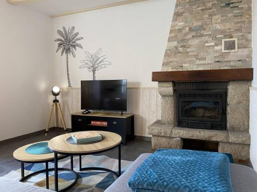 un salon avec une cheminée et une télévision dans l'établissement 903 - Magnifique longère entièrement rénovée quelques kilomètres des plages d'Erquy, à Erquy