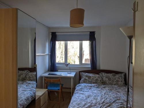Schlafzimmer mit einem Bett, einem Schreibtisch und einem Fenster in der Unterkunft Central and peaceful room with your own bathroom in London