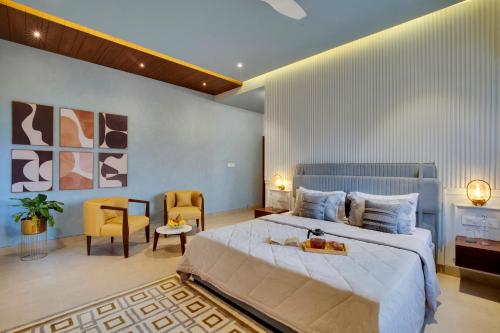 a bedroom with a large bed and a chair at Elivaas Shourya Bliss 3BHK Villa with Pvt Pool, Udaipur in Udaipur