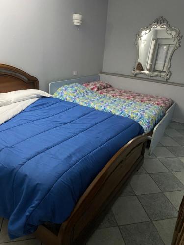 a bed with a blue comforter and a mirror at La casa di Cate & Adry in Envie