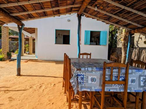 una mesa y sillas bajo el techo de una casa en Chalé brilho do mar, en Icapuí